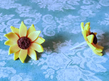 Load image into Gallery viewer, Two sunflower earrings placed on a flat surface one facing forward and one facing sideways.