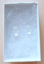 Load image into Gallery viewer, A  pair of clear skull earrings inside a white paper jewelry box.
