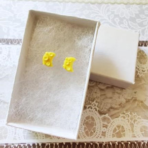 A pair of yellow crescent moons with craters in a white paper jewelry box