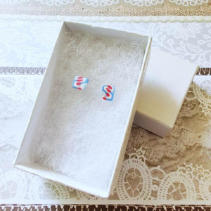 White paper jewelry box with pink, white, and blue earrings