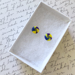 Yellow, blue, and purple swirl earrings inside a white paper jewelry box