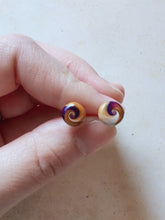 Load image into Gallery viewer, Purple, gold and white swirl earrings held between finger and thumb
