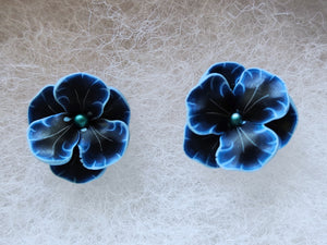 A pair of blue and black flower shaped earrings with blue metallic centers
