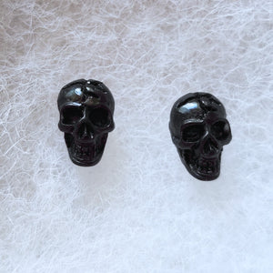 Dark black skull stud earrings.
