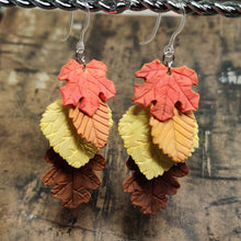 Load image into Gallery viewer, Two dangle earrings with fall leaves cascading down as if stacked on top of each other. A red maple leaf is on top, followed by an orange beech, and yellow aspen, and a brown oak.
