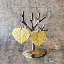 Load image into Gallery viewer, A pair of yellow Aspen leaf shaped polymer clay earrings are displayed hanging from a small, polished silver tree shaped display.
