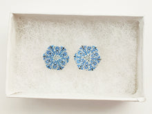 Load image into Gallery viewer, Two hexagon shaped earrings with intricate white, silver and blue patterns inside a white paper jewelry box.
