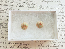 Load image into Gallery viewer, A pair of earrings made to look like sugar cookies decorated with green and red sugar sprinkles. The earrings are inside a white paper earring box. 
