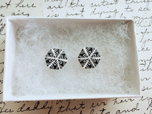 Load image into Gallery viewer, Two hexagon shaped earrings with a snowflake pattern in silver and white. The earrings are inside a white paper jewelry box.
