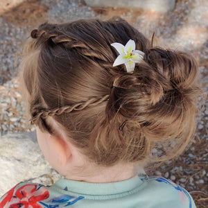 A full hairstyle view of the medium white lily spin in a messy bun hairstyle of blond hair. 