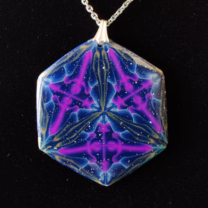 A large hexagonal pendant hanging from a silver chain and bail on a black velvet background. The pendant is navy blue with veins of gold around the edges and radiating from the center in thirds. There are purple veins in the relative shape of a triangle throughout the pendant. 