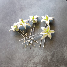 Load image into Gallery viewer, A set of five medium sized white lily hair pins on a mottled grey background.
