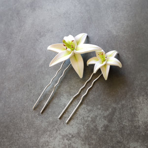 A commparison photograph of a large flower hair pin and a medium flower hair pin. The smaller pin is approximately two thirds the size of the larger one. 
