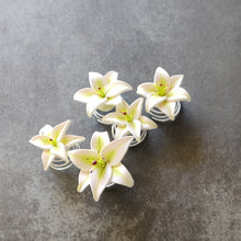 Load image into Gallery viewer, A set of five white lily spin pins. The wire spirals out from the bottom of the flower in a short cone shape. 
