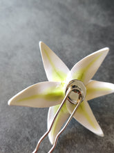 Load image into Gallery viewer, An image showing the back of the white lily hair pin. The silver colored bezel and hair pin are visible with the white petals and green veins showing from the back of the flower.
