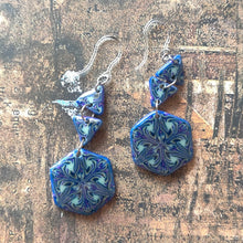 Load image into Gallery viewer, A pair of earrings made of two triangles and a hexagon dangle from two clear plastic ear hooks. 
